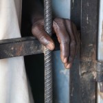 An inmate rests his hand on the bars of a prison controlled by the SLA/Mini Minawi in Shangle Tubaya village in north Darfur October 18, 2010. According to the U.N, the prison currently houses four inmates, who share a cell and are given food twice daily. Of the four, some have been jailed for several weeks without having a trial or legal representatives. Picture taken October 18, 2010. REUTERS/UNAMID/Albert Gonzalez Farran/Handout  (SUDAN - Tags: POLITICS CRIME LAW IMAGES OF THE DAY) FOR EDITORIAL USE ONLY. NOT FOR SALE FOR MARKETING OR ADVERTISING CAMPAIGNS. THIS IMAGE HAS BEEN SUPPLIED BY A THIRD PARTY. IT IS DISTRIBUTED, EXACTLY AS RECEIVED BY REUTERS, AS A SERVICE TO CLIENTS - RTXTM0I
