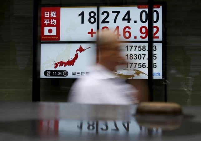 A pedestrian walks past electronic boards showing the Japan's Nikkei average outside a brokerage in Tokyo, Japan, September 9, 2015.  REUTERS/Yuya Shino