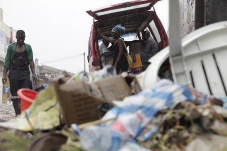 People walk past a pile of garbage along a street during rainfall, in Luanda,  Angola, in this picture taken February 10, 2016.    REUTERS/Herculano Corarado