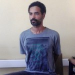 Arthur Simpson-Kent handcuffed behind  at he headquarters of Ghana's Criminal Investigations Department(CID) 1.48 pm, Sunday,  January, 10, 2016.

From: "Justice Lee Adoboe" 
Unshaven  with bushy hear. Spotting a grey T-shirt with the inscription,  "Wilderness" under which is the image of crossed hammers.

He is also in a pair of grey jeans trousers with leather dark leather sandals.