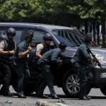 Indonesian police hold rifles while walking behind a car for protection in Jakarta January 14, 2016.  REUTERS/Beawiharta
