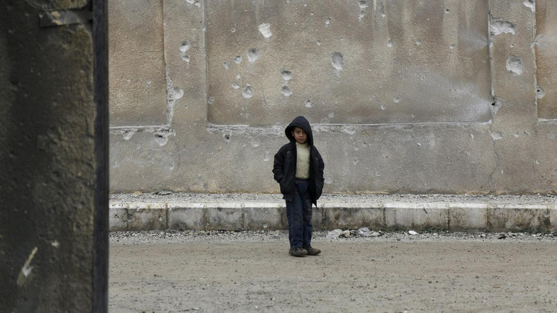 A boy stands near a wall of his school riddled with holes, due to what activists said was an air strike carried out yesterday by the Russian air force in Injara town, Aleppo countryside, Syria January 12, 2016. Bombs dropped by suspected Russian warplanes killed at least 12 Syrian schoolchildren on Monday when they hit a classroom in a rebel-held town in Aleppo province, the Syrian Observatory for Human Rights reported.  REUTERS/Khalil Ashawi