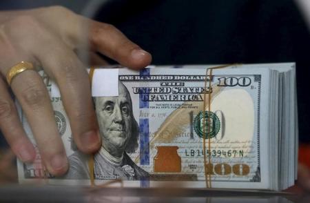 An employee of a money changer holds a stack of U.S.  Dollar notes before giving it to a customer in Jakarta, October 8, 2015   REUTERS/Beawiharta