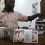 A money dealer counts the Nigerian naira on a machine in his office in the commercial capital of Lagos,  in a file  photo.  REUTERS/Akintunde Akinleye