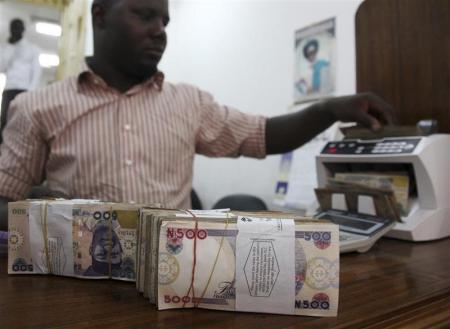A money dealer counts the Nigerian naira on a machine in his office in the commercial capital of Lagos,  in a file  photo.  REUTERS/Akintunde Akinleye