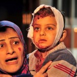 A woman carries an injured boy inside a hospital after multiple bomb blasts hit a southern district of Damascus, Syria, February 21, 2016. REUTERS/SANA