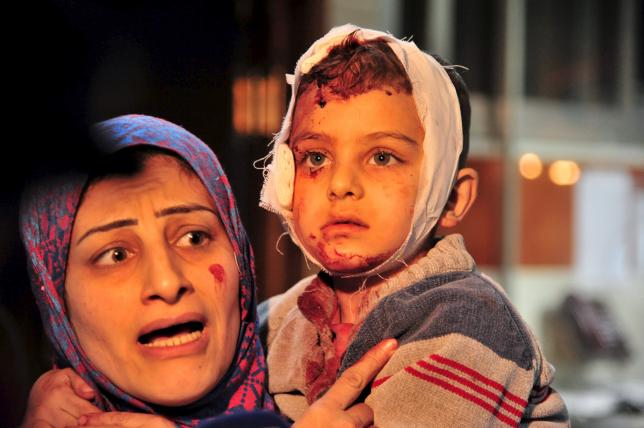 A woman carries an injured boy inside a hospital after multiple bomb blasts hit a southern district of Damascus, Syria, February 21, 2016. REUTERS/SANA