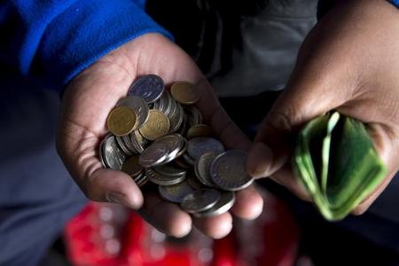 A street trader counts out change for a customer in Durban, September 8, 2015.   REUTERS/Rogan Ward