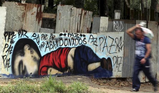 A person walks past a graffiti depicting the drowned Syrian toddler Aylan Kurdi in Sorocaba, Brazil, September 5, 2015. REUTERS/Paulo Whitaker/Files