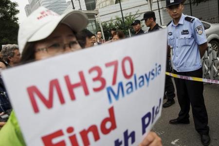 A woman whose relative was aboard Malaysia Airlines flight MH370 holds placard after police stopped protesting relatives from entering a road leading to the Malaysian embassy in Beijing August 7, 2015.   REUTERS/Damir Sagolj
