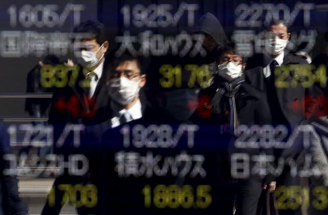 Pedestrians wearing masks are reflected in an electronic board showing various stock prices outside a brokerage in Tokyo, Japan, February 26, 2016.  REUTERS/Yuya Shino