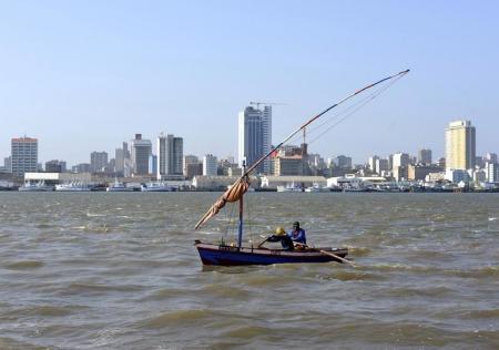 Traditional fishing boats sail as Mozambique's tuna fleet sits in dock beneath Maputo's skyline, in this picture taken August 15, 2015. REUTERS/Grant Lee Neuenburg