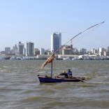 Traditional fishing boats sail as Mozambique's tuna fleet sits in dock beneath Maputo's skyline, in this picture taken August 15, 2015. REUTERS/Grant Lee Neuenburg