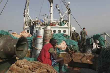 A crew member sits on a fishing net as Sierra Leonean security forces guard the Marampa 803, a vessel apprehended for alleged illegal fishing activities, that has been moored off the West African country's capital Freetown January 21, 2012.     REUTERS/Simon Akam