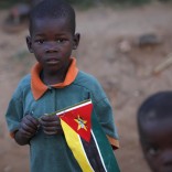 A child clasps a Mozambique flag in a suburb on the outskirt of the capital Maputo in this file picture taken November 2009. At Bobole, a bustling refreshment stop on Mozambique's north-south highway, brightly-painted kiosks lined with bottles offer drinks to thirsty travellers while hawkers sell bananas, paw-paws and carrots in a typical African roadside scene. But memories remain fresh of when Bobole lay in the "death corridor" of a civil war that cost nearly one million Mozambicans their lives until it ended two decades ago. In 2013 a series of hit-and-run raids by opposition Renamo gunmen about 600 km (375 miles) further north has rekindled fears of a return to all-out conflict in what has become one of Africa's economic growth stars. To match Insight MOZAMBIQUE-POLITICS/  REUTERS/Mike Hutchings/Files (MOZAMBIQUE - Tags: SOCIETY POLITICS BUSINESS CIVIL UNREST)
