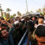 Fighters of Shiite militia group Kataib Hezbollah, with people prepare to deliver the body of a man believed to be Ezzat al-Douri, to the Iraqi government in Baghdad April 20, 2015.  REUTERS/Stringer