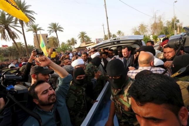 Fighters of Shiite militia group Kataib Hezbollah, with people prepare to deliver the body of a man believed to be Ezzat al-Douri, to the Iraqi government in Baghdad April 20, 2015.  REUTERS/Stringer