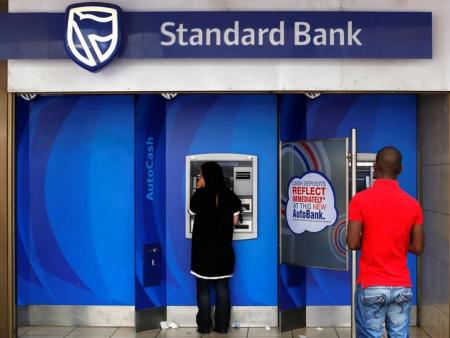 Customers queue to draw money from an ATM outside a branch of South Africa's Standard Bank in Cape Town, March 15, 2016. REUTERS/Mike Hutchings