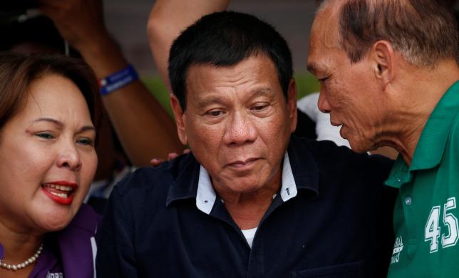 Presidential candidate Rodrigo "Digong" Duterte (C) listens as Senatorial candidates Dionisio Santiago (R) and Sandra Cam talk to him during election campaigning in Malabon, Metro Manila in the Philippines April 27, 2016.    REUTERS/Erik De Castro