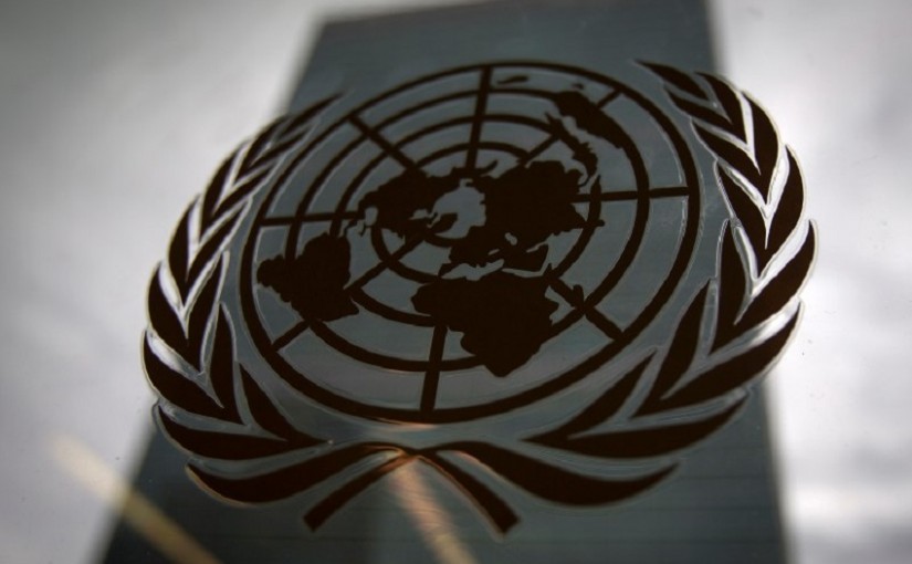 The United Nations headquarters building is pictured though a window with the UN logo in the foreground in the Manhattan borough of New York August 15, 2014.    REUTERS/Carlo Allegri