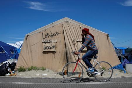 An immigrant bicycles past a tent with the message, "London My Dream" in the make-shift immigrant camp, called the jungle,  in Calais, France, after Britain's referendum results to leave the European Union were announced June 24, 2016.    REUTERS/Pascal Rossignol