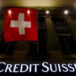 The logo of Swiss bank Credit Suisse is seen below the Swiss national flag at a building in the Federal Square in Bern, Switzerland, May 15, 2014. REUTERS/Ruben Sprich/File Photo
