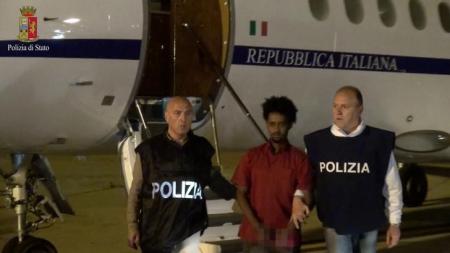 Medhanie Yehdego Mered (C), 35, is pictured with Italian policemen as they land at Palermo airport, Italy, following his arrest in Khartoum, Sudan, on May 24. Picture released on June 8, 2016 by Italian Police Department. Image pixellated at source. Italian Police Department/Handout via REUTERS