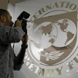A photographer takes pictures through a glass carrying the International Monetary Fund (IMF) logo during a news conference in Bucharest,  file.    REUTERS/Bogdan Cristel