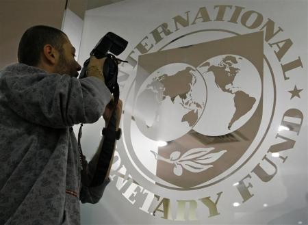A photographer takes pictures through a glass carrying the International Monetary Fund (IMF) logo during a news conference in Bucharest,  file.    REUTERS/Bogdan Cristel