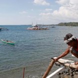 A fisherman repairs his boat overlooking fishing boats that fish in the disputed Scarborough Shoal in the South China Sea, at Masinloc, Zambales, in the Philippines April 22, 2015. REUTERS/Erik De Castro