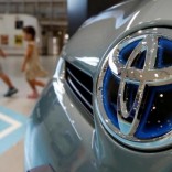 Visitors walk past a logo of Toyota Motor Corp on a Toyota Prius hybrid vehicle at the company's showroom in Tokyo August 5, 2014.   REUTERS/Yuya Shino/File Photo