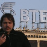 A man walks in a street, with the logo of VTB Bank displayed on the roof of a building, in Moscow, November 20, 2014.   REUTERS/Maxim Zmeyev