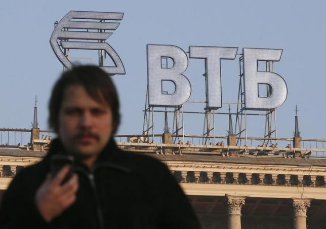 A man walks in a street, with the logo of VTB Bank displayed on the roof of a building, in Moscow, November 20, 2014.   REUTERS/Maxim Zmeyev