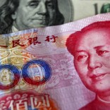 A yuan banknote is displayed next to a U.S. dollar banknote (back) for the photographer at a money changer inside the Taoyuan International Airport in this March 18, 2010 file photo.    REUTERS/Nicky Loh/Files