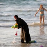 A Muslim woman wearing a hijab stands in the waters in the Mediterranean Sea as an Israeli stands nearby on the beach in Tel Aviv, Israel August 21, 2016. REUTERS/Baz Ratner