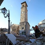 Rescuers walk past the bell tower with the clock showing the time of the earthquake in Amatrice, central Italy, August 24, 2016. REUTERS/Stefano Rellandini