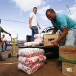 Men load boxes of food onto the back of a pick-up truck, after arriving from Brazil, in front of the bus terminal in Santa Elena de Uairen, Venezuela August 2, 2016. REUTERS/William Urdaneta