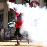 A Zimbabwean man throws back a tear gas cannister during a protest by opposition youths who were demonstrating against alleged brutality by security agents in the capital Harare, August 24, 2016.   REUTERS/Philimon Bulawayo