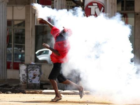 A Zimbabwean man throws back a tear gas cannister during a protest by opposition youths who were demonstrating against alleged brutality by security agents in the capital Harare, August 24, 2016.   REUTERS/Philimon Bulawayo