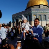 A Palestinian man holds his child who is dressed in festive clothes following morning prayers marking the first day of Eid al-Adha celebrations, on the compound known to Muslims as al-Haram al-Sharif and to Jews as Temple Mount in Jerusalem's Old City September 12, 2016. REUTERS/Ammar Awad