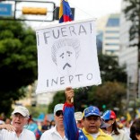 An opposition supporter takes part in a rally to demand a referendum to remove Venezuela's President Nicolas Maduro while carrying a sign that reads "Go out, inept" in Caracas, Venezuela, September 1, 2016.  REUTERS/Christian Veron