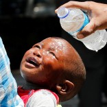 A woman pours water over a child affected by teargas after clashes between police and street vendors in central Harare, Zimbabwe, September 27, 2016. REUTERS/Philimon Bulawayo