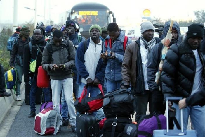 Migrants with their belongings queue near buses at the start of their evacuation and transfer to reception centers in France, and the dismantlement of the camp called the "Jungle" in Calais, France, October 24, 2016.     REUTERS/Pascal Rossignol