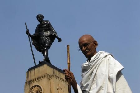 Mahesh Chaturvedi, 63, who dresses up like Mahatma Gandhi, poses for a photo in front of a statue of Gandhi in the old quarters of New Delhi October 25, 2012.   REUTERS/Mansi Thapliyal