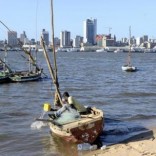 A fisherman cleans his boat beneath Maputo's skyline, in this picture taken August 15, 2015.  REUTERS/Grant Lee Neuenburg
