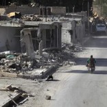 A rebel fighter rides past damaged buildings in al-Rai town, northern Aleppo countryside, Syria October 2, 2016. REUTERS/Khalil Ashawi