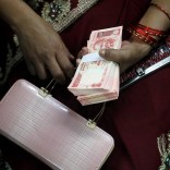A woman holds 20 Indian rupees banknotes after exchanging them with old high denomination banknotes at a bank in Allahabad, November 13, 2016. REUTERS/Jitendra Prakash