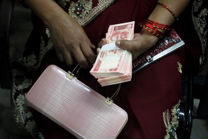 A woman holds 20 Indian rupees banknotes after exchanging them with old high denomination banknotes at a bank in Allahabad, November 13, 2016. REUTERS/Jitendra Prakash