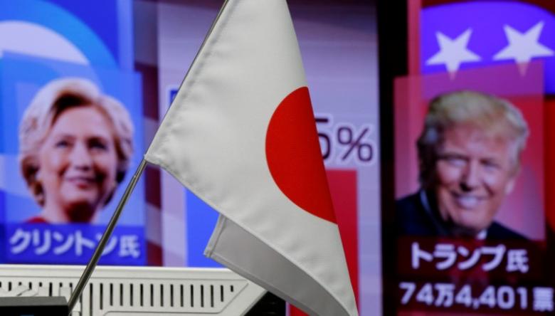 A Japanese national flag is seen in front of a monitor displaying Hillary Clinton and Donald Trump on TV news at a foreign exchange trading company in Tokyo, Nov. 9, 2016.   REUTERS/Toru Hanai
