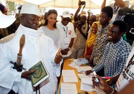 Gambian President Yahya Jammeh holds a copy of the Quran while speaking to a poll worker at a polling station during the presidential election in Banjul, Gambia, December 1, 2016. REUTERS/Thierry Gouegnon